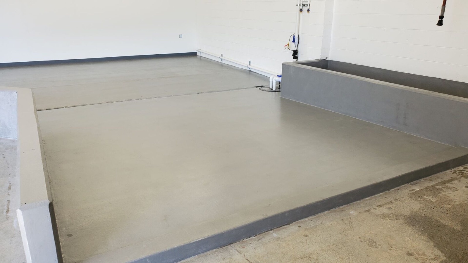 CrossLinker floor coating freshly applied to a concrete floor and containment curb