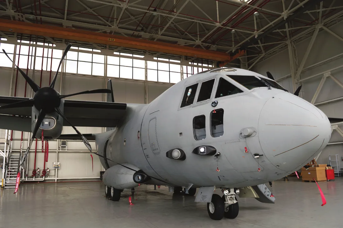 Military transport aircraft parked inside a maintenance hangar with a smooth, light gray floor