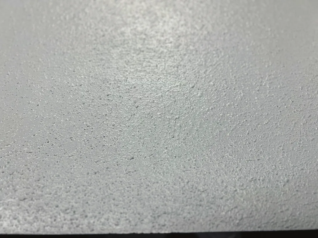 Close-up of a light gray floor coating with a fine, evenly textured non-slip surface, photographed across a slab edge
